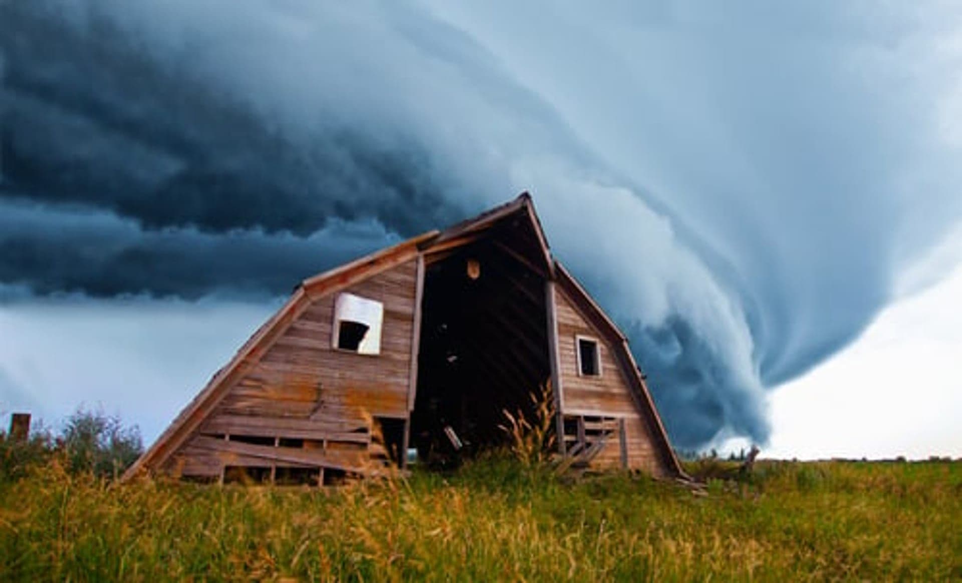 Severe Kansas storm cloud rolling over open country near a rural barn