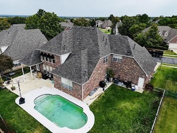 Aerial view of a new architectural shingle roof on a brick home with backyard pool in South-Central Kansas