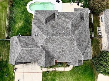 Overhead drone photo of a completed hip roof shingle replacement on a large Wichita home with pool