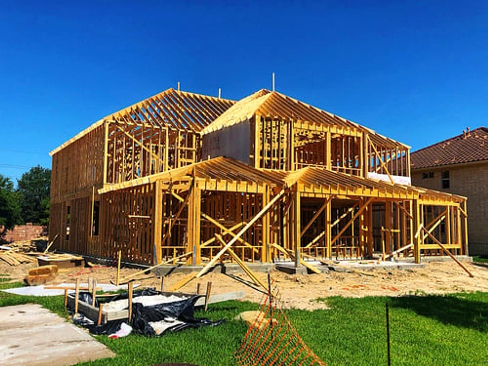 Residential new construction framing under a clear blue sky on a Global Roofing and Construction job site in Kansas